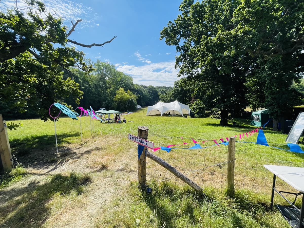 A Hoodstock field entrance with tents, trees and bunting