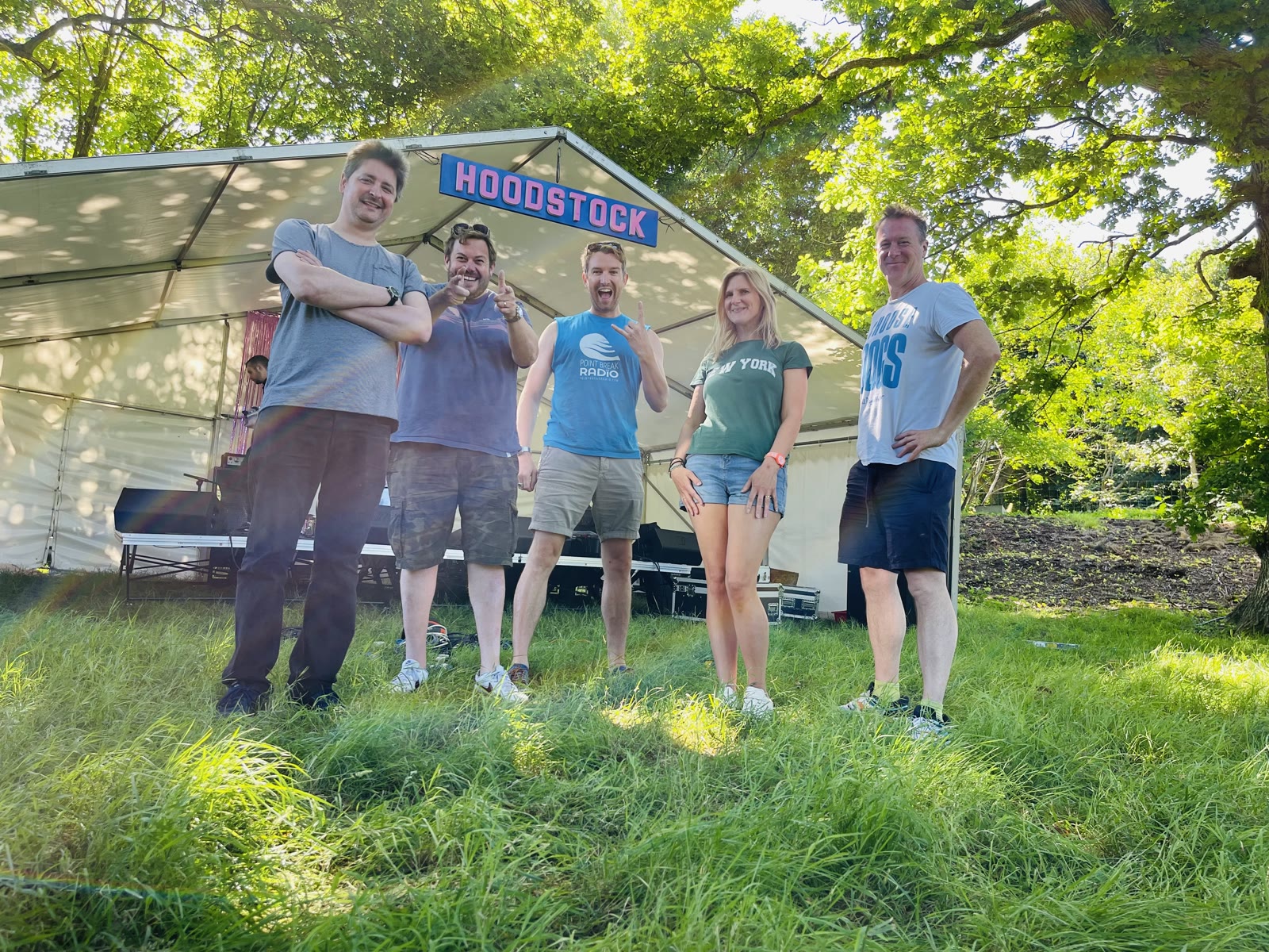 A group of Hoodstock organisers standing beneath the Hoodstock sign